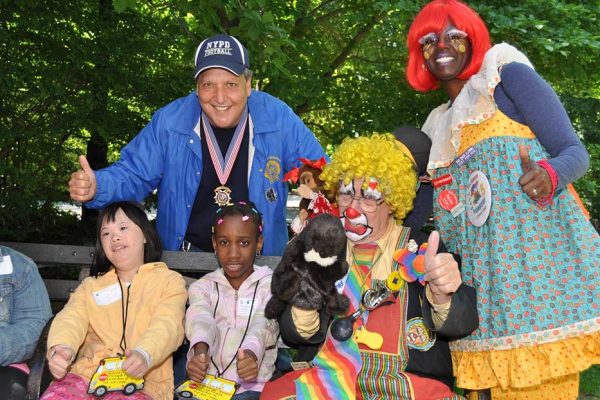 Community Mayors volunteer, clowns and children sitting on park bench