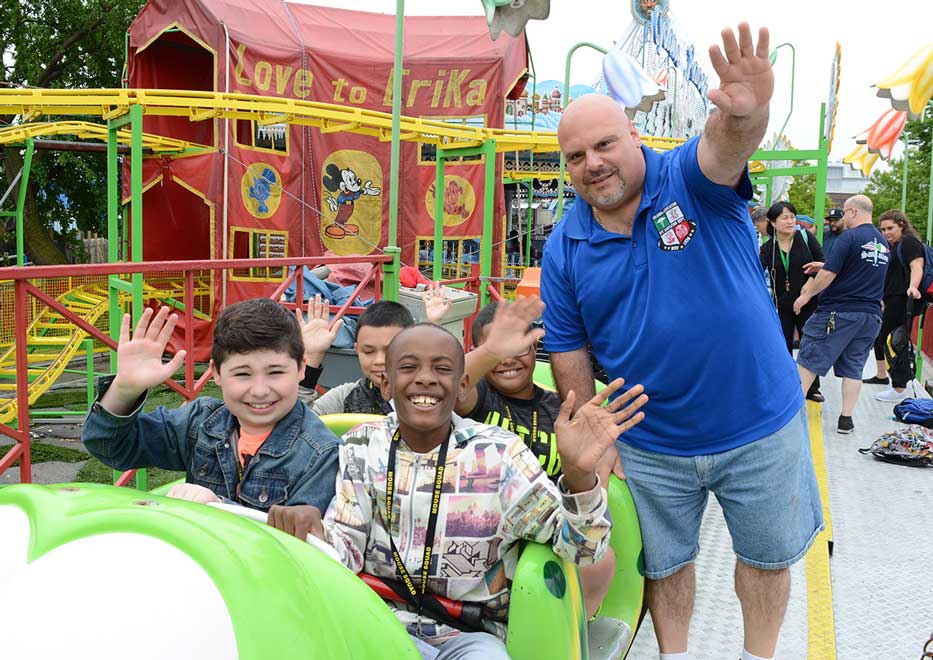Community Mayors volunteer with group of children riding an amusement park ride