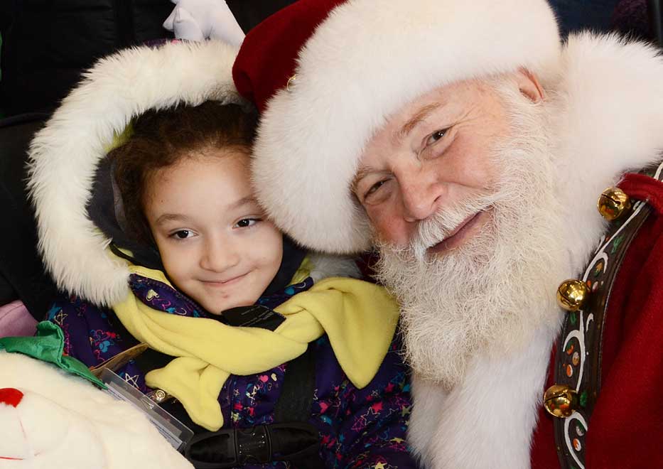 Little girl and Macy's iconic Santa Claus smiling at Operation Santa Claus event