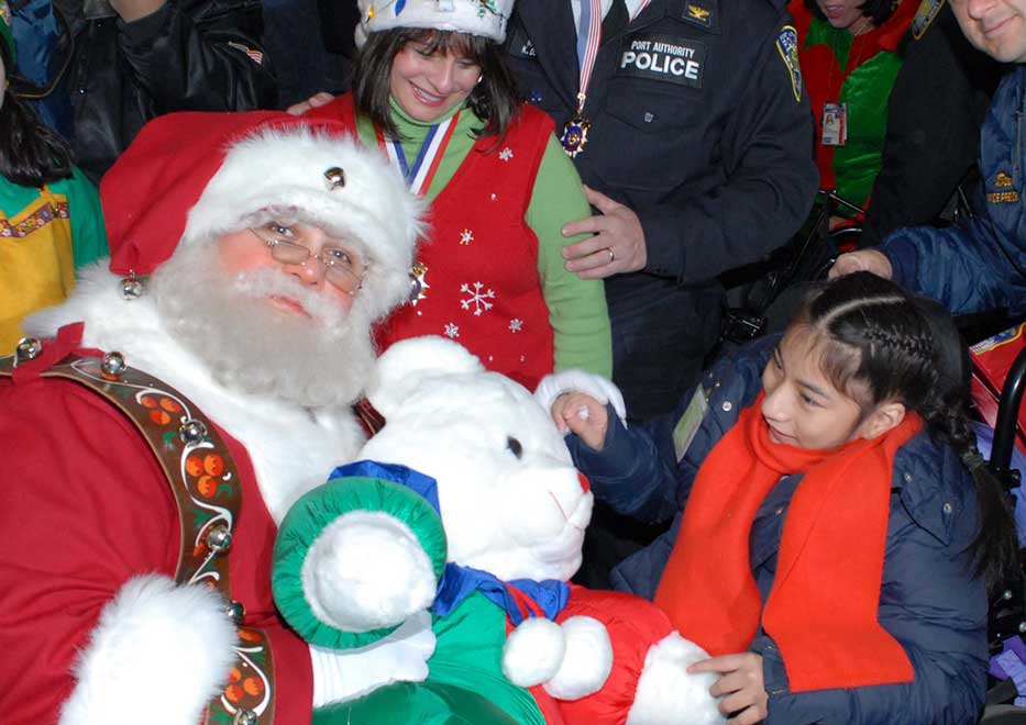 Santa Claus giving a little girl a gift at Community Mayor's Operation Santa Claus special event