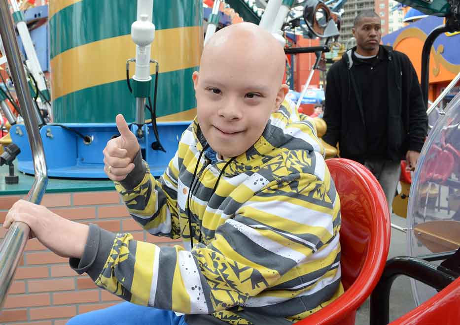 Child with "thumbs up" gesture enjoying an amusement park ride